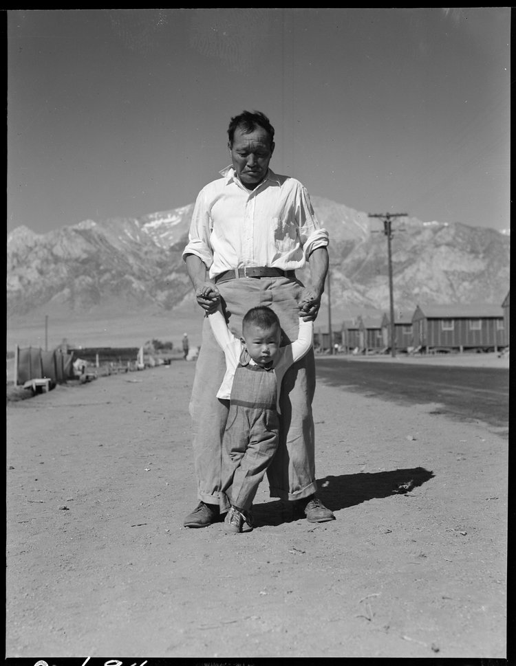 Manzanar Relocation Center, Manzanar, California. Grandfather of Japanese ancestry teaching his little grandson to walk at this War Relocation Authority center for evacuees.