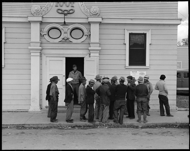 Byron, California. Field laborers of Japanese ancestry from a large delta ranch have assembled at Wartime Civil Control Administration station to receive instructions for evacuation which is to be effective in three days under Civilian Exclusion Order Number 24. They are arguing together about whether or not they should return to the ranch to work for the remaining five days or whether they shall spend that time on their personal affairs.
