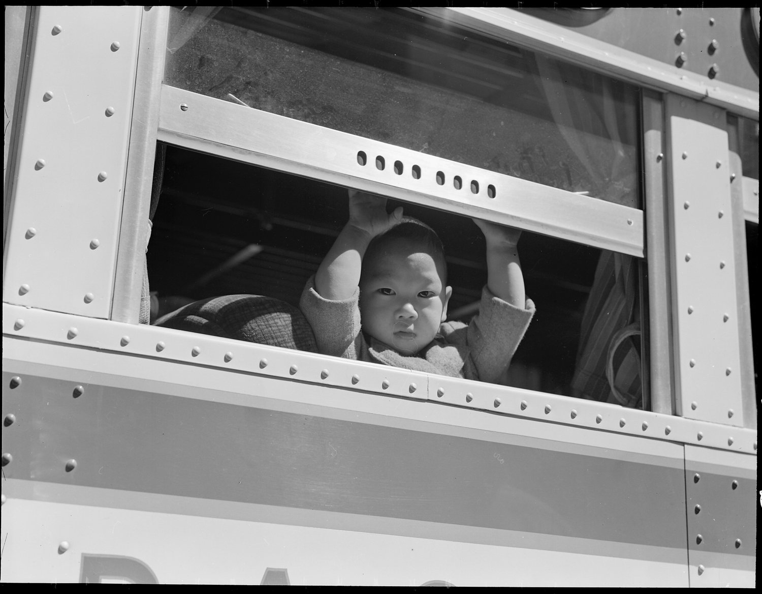 San Francisco, California. A young evacuee looks out the window of bus before it starts for Tanforan Assembly center. Evacuees will be transferred to War Relocation Authority centers for the duration.
