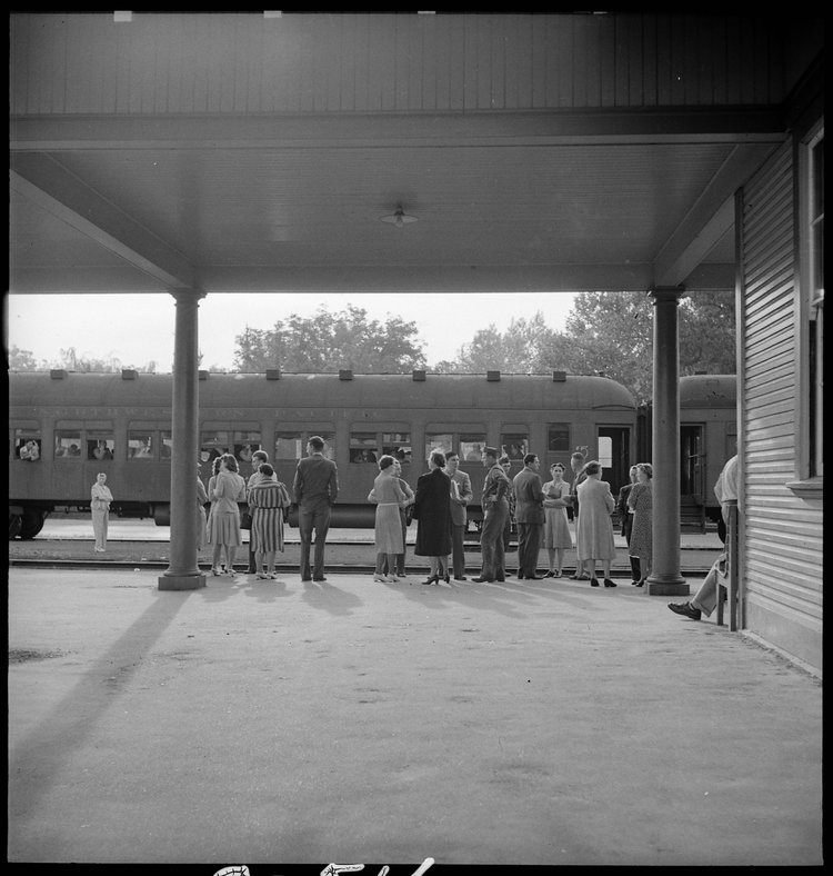 Woodland, California. This staff of Wartime Civil Control Administration workers have completed their job and stand on the platform awaiting the departure of the special train which has been loaded with evacuees of Japanese ancestry bound for the Merced Assembly center, 125 miles away.