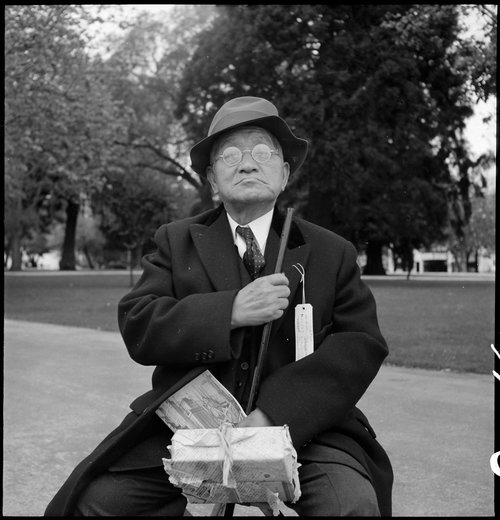 Hayward, California. Grandfather of Japanese ancestry waiting at local park for the arrival of evacuation bus which will take him and other evacuees to the Tanforan Assembly center. He was engaged in the Cleaning and Dyeing business in Hayward for many years.